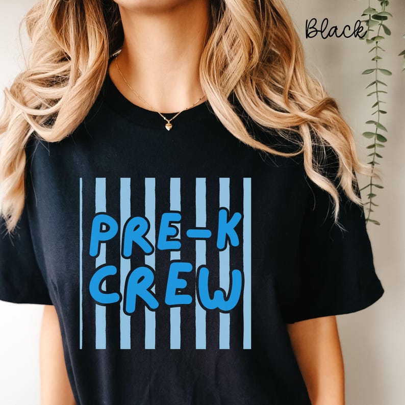 May include: Black t-shirt featuring the text "PRE-K CREW" in blue, with a white outline, set against a backdrop of vertical blue stripes. The word "Black" is written in cursive in the top right corner.