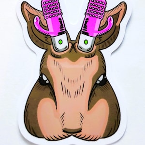 May include: A sticker featuring a cartoon deer head with pink vibrators replacing the antlers. The deer has brown fur, a pink nose, and green eyes. The sticker has a white border.