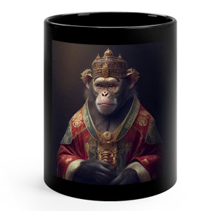 Può includere: Una tazza da caffè nera con un'illustrazione digitale di uno scimpanzé che indossa una corona d'oro e una veste rosso e oro. Lo scimpanzé ha un'espressione seria sul viso.
