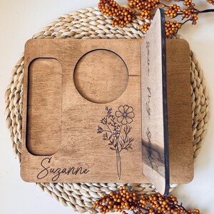 May include: A personalized wooden tray with a cutout for a mug, a phone slot, and a floral design. The tray is engraved with the name "Suzanne" and the text "Starts a New Chapter".