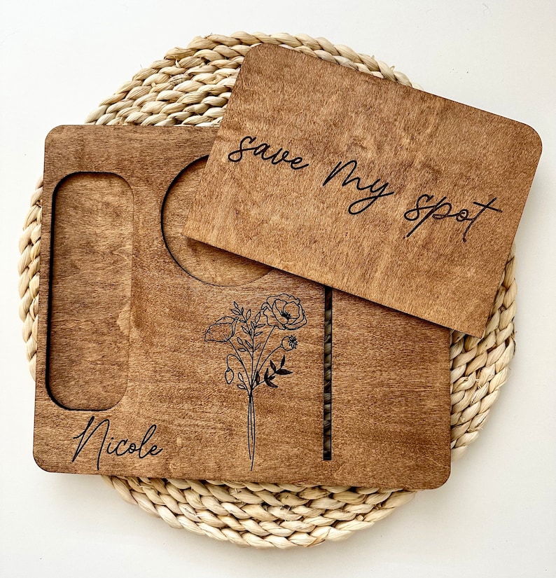 May include: A wooden tray with a cutout for a drink and a small plate. The tray has a floral design and the text "Nicole" and "Save My Spot" engraved on it.