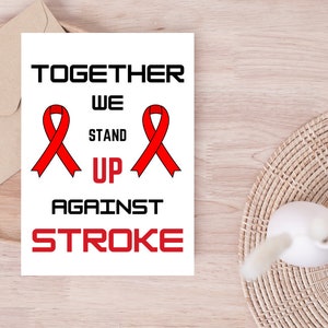 May include: White card with the text "TOGETHER WE STAND UP AGAINST STROKE" in black letters. Two red awareness ribbons are on either side of the text.