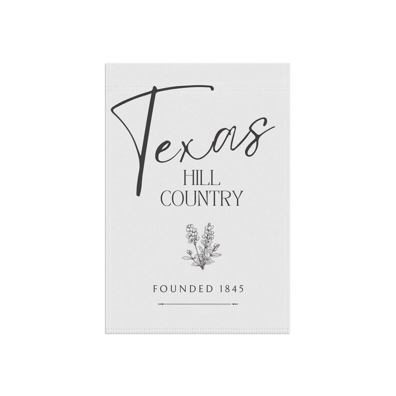 May include: A white rectangular sign featuring the text "Texas Hill Country" in a black script font. Below the text is a floral illustration and the words "Founded 1845". The sign has a minimalist design.