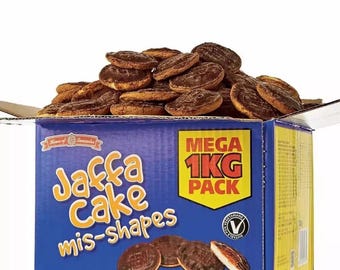 May include: A blue box filled with Jaffa Cake mis-shapes. The box is labeled "Jaffa Cake mis-shapes" and "Mega 1KG Pack". The box is also labeled "1000g e" and has a green "Vegetarian" symbol.
