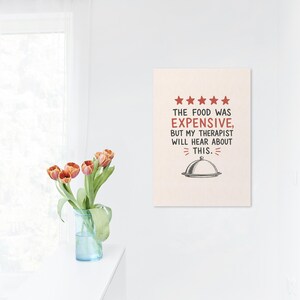 May include: A rectangular wall art print featuring five red stars above the black text THE FOOD WAS EXPENSIVE, BUT MY THERAPIST WILL HEAR ABOUT THIS. Below the text is a black and white illustration of a domed food serving platter.
