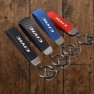 May include: Four keychains with loops in black, carbon fiber pattern, blue, and red. Each loop features the white text CIVIC and is attached to a gunmetal-colored metal clasp and ring assembly. The black loop has red stitching along the edges.