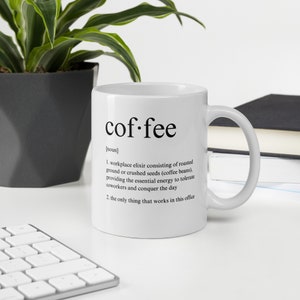 May include: White ceramic coffee mug with the word "coffee" in a black, bold font. The mug includes a definition of coffee, describing it as an elixir and the only thing that works in the office.