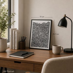 May include: A framed black and white abstract line art print in portrait orientation. The artwork measures 21 cm by 29.7 cm. The print features a dense, intricate pattern of various shapes and lines, presented in a simple black frame.