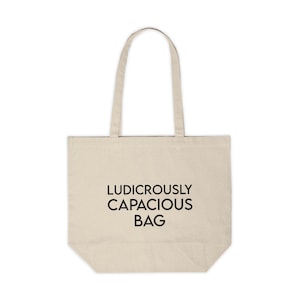 May include: A beige canvas tote bag with black text that reads "Ludicrously Capacious Bag".