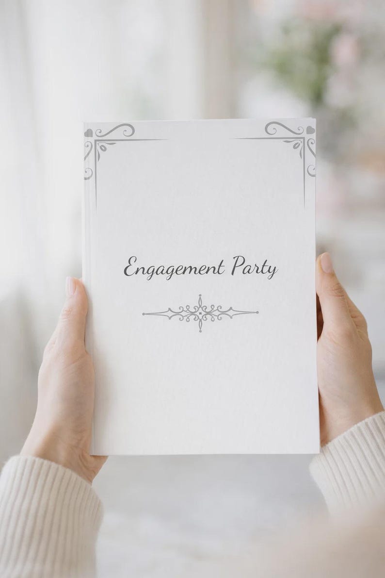 K&ouml;nnte beinhalten: Ein wei&szlig;es rechteckiges Buch mit dem in Schwarz gedruckten Text Engagement Party in der Mitte. Der Einband zeigt graue dekorative Schn&ouml;rkel an den Ecken und ein zentriertes graues ornamentales Verzierungsdesign unter dem Text.