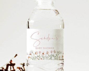 May include: A clear plastic water bottle with a white label that says "Sandra's Baby Shower" in pink script. The label also features a floral design with pink and white flowers.