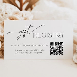Op de afbeelding: Een witte kaart met zwarte tekst die "gift registry" luidt. De tekst "Sandra is registered at Amazon." staat onder de titel. Daaronder staat de tekst "Please scan the QR code to view the gift registry." Rechts van de tekst staat een zwart-witte QR-code.