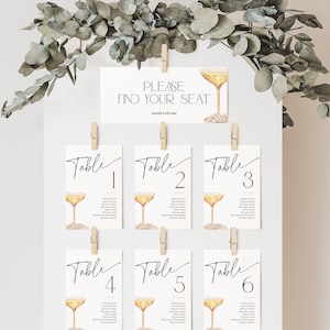 May include: White card with the text "PLEASE FIND YOUR SEAT" and a champagne glass illustration. Six smaller white cards with the text "Table" and numbers 1 through 6, each with a champagne glass illustration.