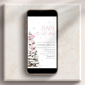 May include: A digital invitation for a baby shower with a winter theme. The invitation features a watercolor illustration of a snowy pine tree with a pink ribbon and the text "Baby it's cold outside". The invitation is for Sandra Miller and the shower is scheduled for December 14th at 2:00 pm at the Lily Rose Residence.