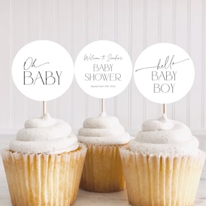 Pode incluir: Três toppers de cupcake brancos com texto preto. Os toppers dizem "Oh Baby", "Bem-vindo ao Chuveiro de Bebê da Sandra em 14 de setembro de 20xx" e "Olá Bebê Menino".
