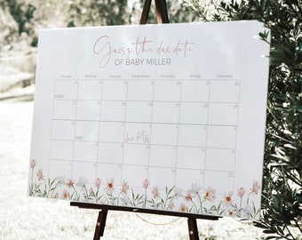 Könnte beinhalten: Ein weißer Kalender mit floralem Rand, auf einem Staffelei aufgestellt. Der Kalender trägt den Titel "Erraten Sie das Geburtsdatum von Baby Miller" und zeigt die Monate April und Mai.