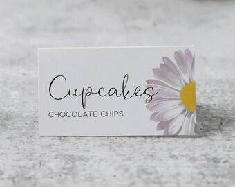 Op de afbeelding: Witte kaart met de tekst "Cupcakes" in zwarte cursieve letters en "Chocolate Chips" in zwarte letters eronder. Een witte madeliefje met een gele kern is gedeeltelijk zichtbaar in de rechterbovenhoek van de kaart.