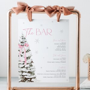 May include: A copper-colored metal framed bar menu with a watercolor Christmas tree design. The menu includes drink options and is decorated with pink bows. A copper mug and liquor bottle are in the background.