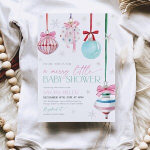 May include: A baby shower invitation with a winter theme. The invitation features a watercolor illustration of Christmas ornaments in pink, blue, and green colors. The text on the invitation reads "Please join us for a merry little baby shower honoring the mom-to-be Sandra Miller December 14th, 20XX at 4PM 301 Wildflower Lane, Bloomingville Please RSVP to Melanie 01234-56789 Registered at Amazon and Target"