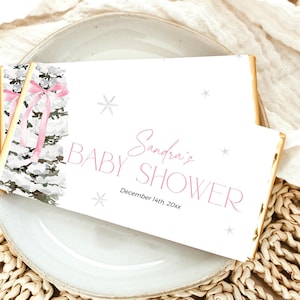 May include: White chocolate bar wrapper with a winter-themed design. The wrapper features a watercolor illustration of a birch tree with pink ribbons and snowflakes. The text "Sandra's Baby Shower" and "December 14th, 20xx" is printed on the wrapper.