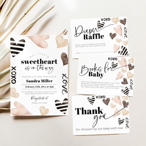 May include: A set of four baby shower cards featuring a watercolour heart design. The cards include a diaper raffle, books for baby, a thank you card, and a baby shower invitation. The invitation reads "Our little sweetheart is on the way" and includes the date and time of the shower. The cards are decorated with hearts in shades of pink, brown, and gold.
