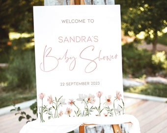 May include: White welcome sign with pink floral border and the text "Welcome to Sandra's Baby Shower 22 September 2023".