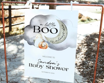 Puede incluir: Un letrero de bienvenida para una fiesta de bienvenida al bebé con temática de Halloween. El letrero presenta un diseño de acuarela con un fantasma, una calabaza y las palabras "a little BOO is almost due". El letrero también incluye el nombre "Sandra's Baby Shower" y la fecha.