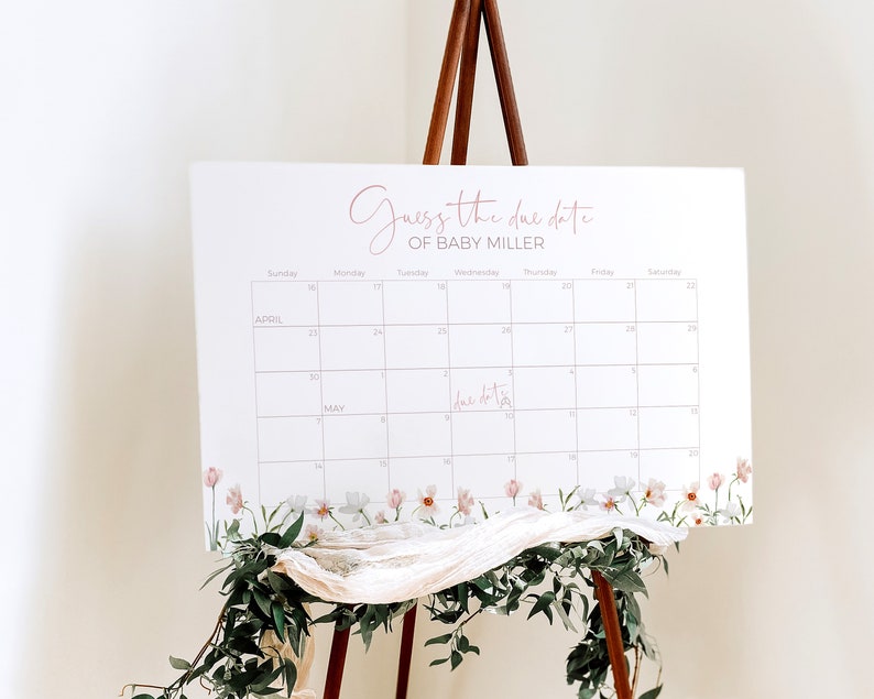 May include: A white calendar with a floral border, featuring a pink script that says "Guess the due date of Baby Miller". The calendar is set up for April and May, with the due date marked on the calendar.