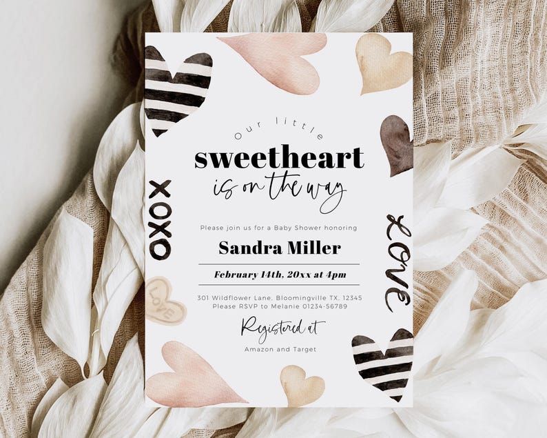 May include: A baby shower invitation with a white background and black and white hearts. The text reads "Our little sweetheart is on the way." The invitation also includes the date, time, and location of the shower. The text "Registered at Amazon and Target" is also included.