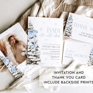 May include: Winter-themed baby shower invitation and thank you card set with a blue and white watercolor design featuring a snowy pine tree. The invitation includes the text "Baby it's cold outside" and the thank you card says "Thank you for showering our baby with love".