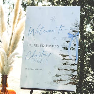 May include: A white sign with blue text and a watercolor illustration of a blue Christmas tree with a blue ribbon. The sign says "Welcome to The Miller Family's Christmas Party December 18th, 20xx".