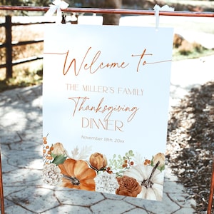May include: A white sign with the words "Welcome to The Miller's Family Thanksgiving Dinner" in elegant script. The sign is decorated with watercolor pumpkins, flowers, and foliage. The date is November 18th, 20xx. The sign is displayed on a copper-colored metal stand.
