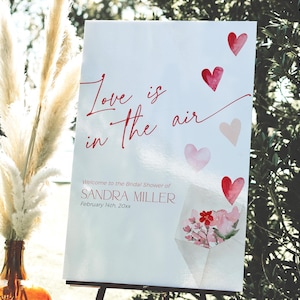 Modelo de placa de boas-vindas para chá de panela de dia dos namorados, sinalização Coquette Love is in the Air, decoração de despedida de solteira de fevereiro com corações vermelhos e rosas, CH83