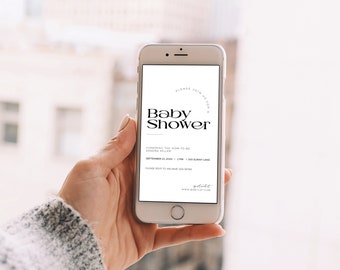 May include: A white smartphone displaying a baby shower invitation with black text. The invitation reads "Please join us for a Baby Shower" and includes the honoree's name, date, time, and location. The invitation also includes a website address for the baby registry.