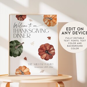 May include: A framed Thanksgiving dinner sign with watercolor pumpkins in shades of orange, red, and green. The sign reads "Welcome to our Thanksgiving Dinner" and includes editable text. The sign is displayed on a light-colored table.