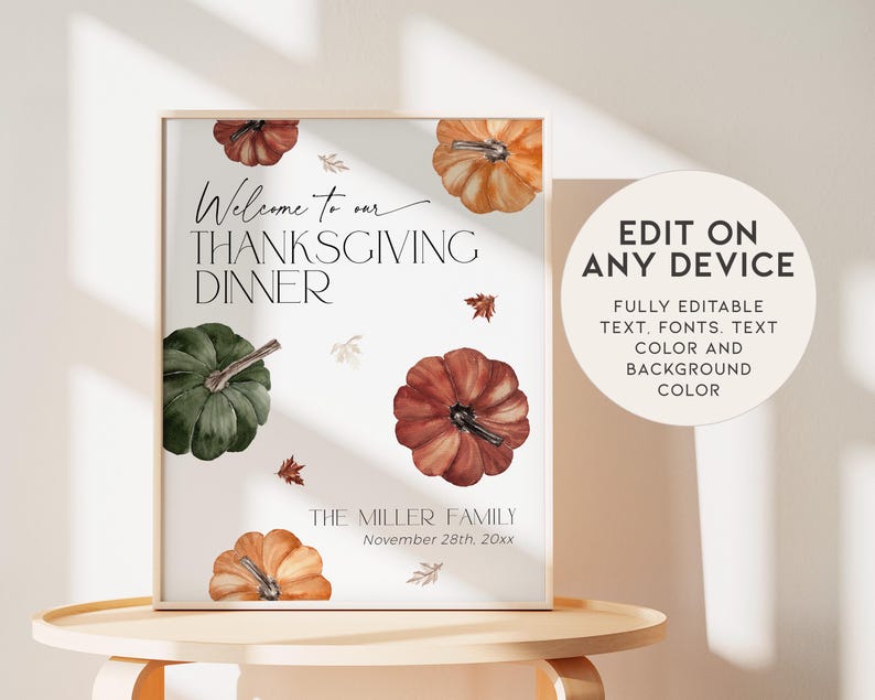 May include: A framed Thanksgiving dinner sign with watercolor pumpkins in shades of orange, red, and green. The sign reads "Welcome to our Thanksgiving Dinner" and includes editable text. The sign is displayed on a light-colored table.