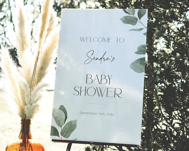 May include: White sign with green watercolor leaves and the text "Welcome to Sandra's Baby Shower September 14th, 20xx".