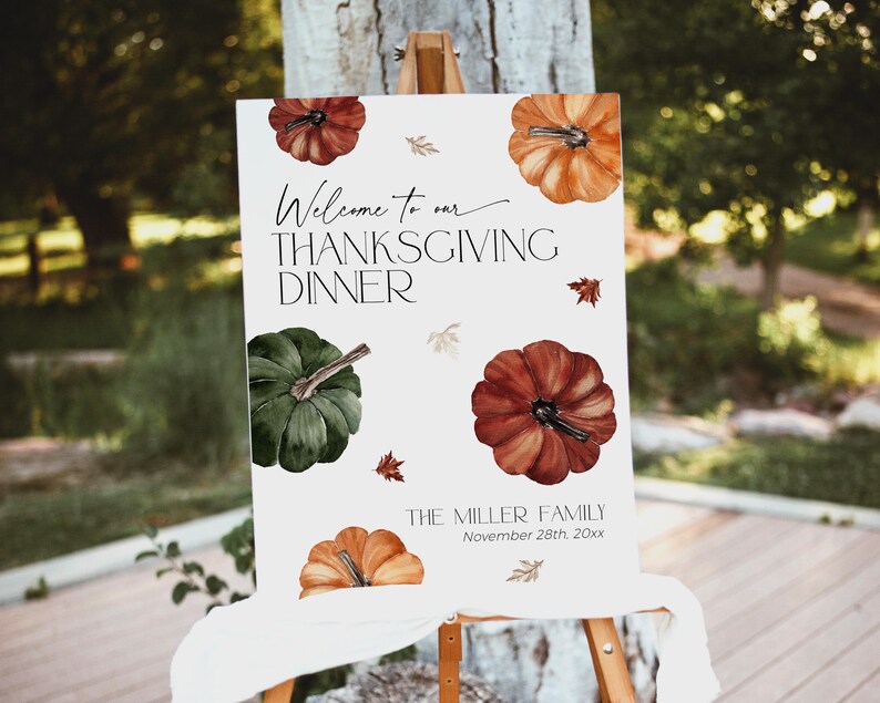 May include: Thanksgiving dinner welcome sign with watercolor pumpkins in shades of orange, red, and green. The sign reads "Welcome to our Thanksgiving Dinner" and includes the family name and date.
