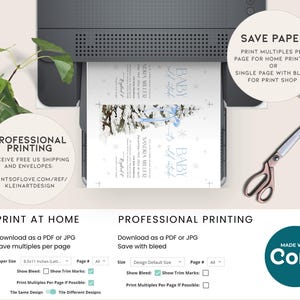 May include: A digital mockup of a baby shower invitation with a winter theme. The invitation features a blue and white color scheme with a watercolor illustration of a snowy forest and a baby carriage. The text on the invitation reads "Baby it's cold outside". The invitation is being printed on a printer with a white background.