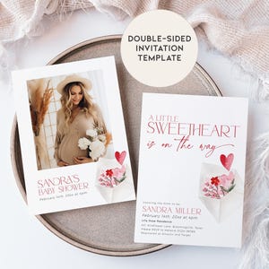 May include: Double-sided baby shower invitation template featuring a watercolour illustration of a pink and red envelope with flowers and a heart. The text on the front reads "A little sweetheart is on the way". The back of the invitation features a photo of a pregnant woman in a beige dress and a floral bouquet. The text on the back reads "Sandra's Baby Shower, February 14th, 20xx at 4pm".
