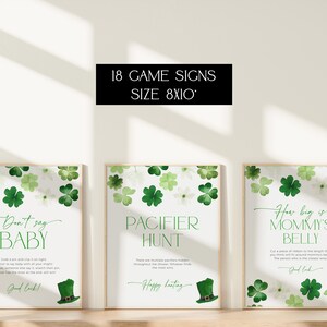 May include: Three printable game signs for a baby shower. The signs are white with green shamrock designs and have the text "Don't say baby", "Pacifier Hunt", and "How big is Mommy's Belly".