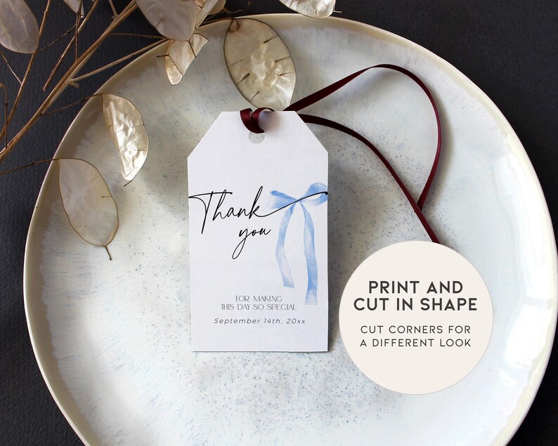Pode incluir: Uma etiqueta de agradecimento branca com um la&ccedil;o de aquarela azul e o texto "Obrigado" em caligrafia preta. A etiqueta tamb&eacute;m inclui o texto "Por tornar este dia t&atilde;o especial" e "Setembro 14th, 20xx". Um c&iacute;rculo branco com texto preto diz "Imprima e corte na forma. Corte os cantos para um visual diferente."