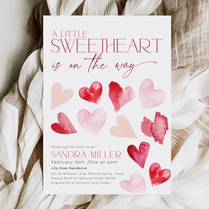 May include: A baby shower invitation with a watercolor design featuring pink and red hearts. The text reads "A Little Sweetheart is on the way" and includes the name Sandra Miller, the date February 14th, the time 4pm, and the location Lilly Rose Residence.