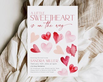May include: A baby shower invitation with a watercolor design featuring pink and red hearts. The text reads "A Little Sweetheart is on the way" and includes the name Sandra Miller, the date February 14th, the time 4pm, and the location Lilly Rose Residence.