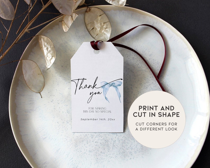 Pu&ograve; includere: Un'etichetta di ringraziamento bianca con un fiocco blu acquerellato e il testo "Grazie" in calligrafia nera. L'etichetta include anche il testo "Per aver reso questa giornata cos&igrave; speciale" e "Settembre 14th, 20xx". Un cerchio bianco separato con testo nero dice "Stampa e ritaglia in forma" e "Taglia gli angoli per un aspetto diverso".