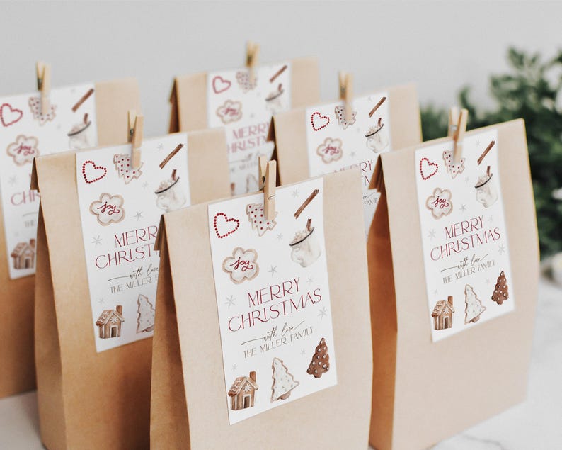 Puede incluir: Bolsas de regalo de papel marr&oacute;n con etiquetas de regalo blancas. Las etiquetas tienen un dise&ntilde;o de acuarela de galletas de jengibre, una taza de chocolate caliente y un &aacute;rbol de Navidad. El texto en las etiquetas dice "Feliz Navidad con amor de la familia Miller".