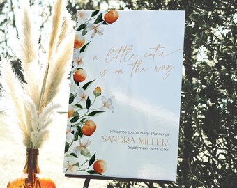 May include: A white welcome sign with orange blossoms and fruit. The text reads "a little cutie is on the way" and "Welcome to the Baby Shower of SANDRA MILLER September 14th, 20xx".