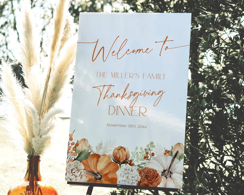 May include: A Thanksgiving dinner welcome sign with the text "Welcome to The Miller's Family Thanksgiving Dinner November 18th, 20xx." The sign features a floral design with pumpkins, roses, and berries in shades of orange, white, and brown.
