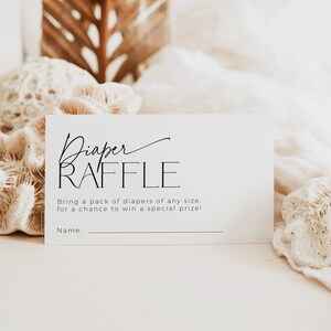 May include: A white card with black text that reads "Diaper Raffle" and "Bring a pack of diapers of any size, for a chance to win a special prize!" with a blank line for a name.