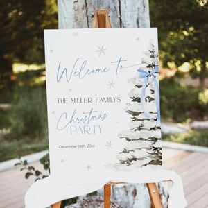 May include: A white welcome sign with blue text and a watercolor illustration of a Christmas tree with a blue ribbon. The sign reads "Welcome to The Miller Family's Christmas Party December 18th 20xx".